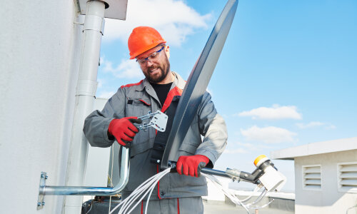 Mann montiert SAT-Anlage